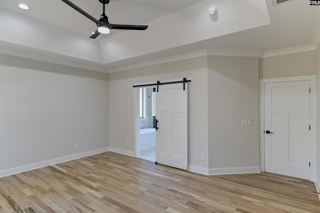 spare room featuring ceiling fan, baseboards, light wood-style floors, and a barn door