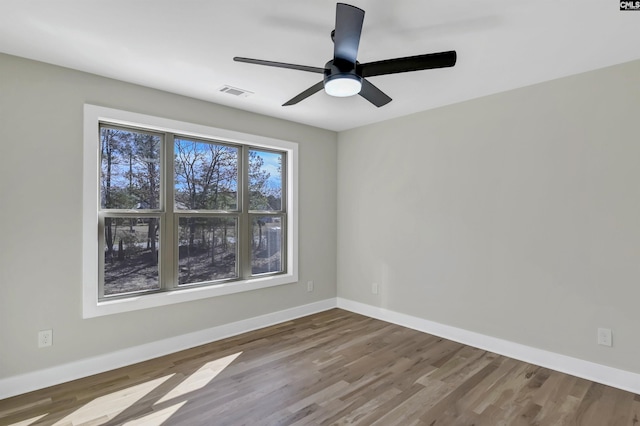 spare room with visible vents, baseboards, wood finished floors, and a ceiling fan