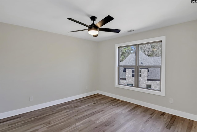 empty room with visible vents, baseboards, wood finished floors, and a ceiling fan