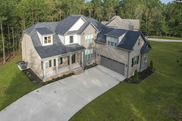 view of front of property with a view of trees, covered porch, concrete driveway, and a front yard