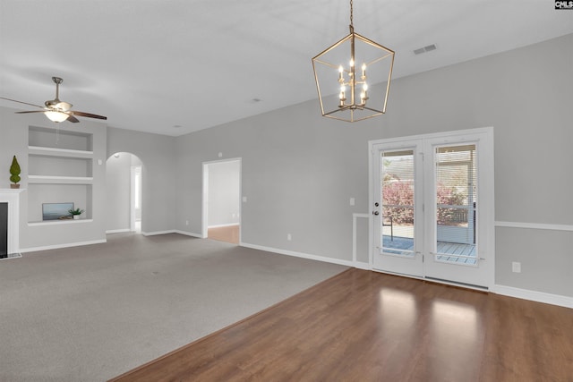 unfurnished living room featuring visible vents, baseboards, built in features, a fireplace with flush hearth, and arched walkways