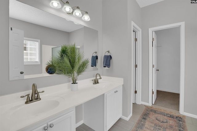 bathroom featuring double vanity, baseboards, and a sink