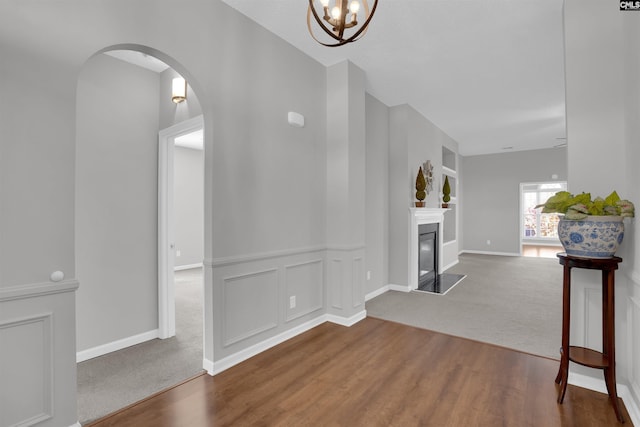 interior space with baseboards, carpet flooring, wood finished floors, arched walkways, and a glass covered fireplace