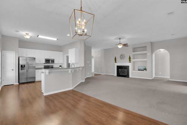 kitchen with built in features, a breakfast bar, arched walkways, stainless steel appliances, and white cabinetry