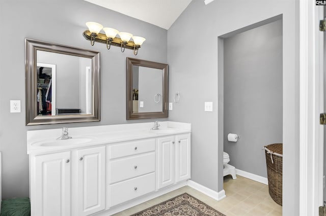 bathroom with double vanity, toilet, baseboards, and a sink