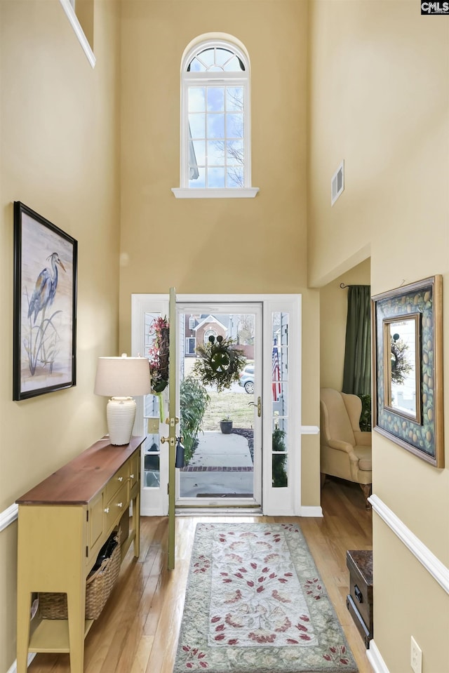 entrance foyer with visible vents, a high ceiling, and hardwood / wood-style flooring