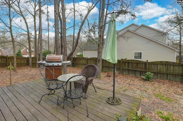 wooden terrace with area for grilling and a fenced backyard