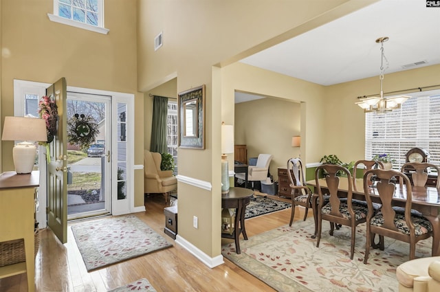 foyer with visible vents, wood finished floors, a healthy amount of sunlight, and a chandelier