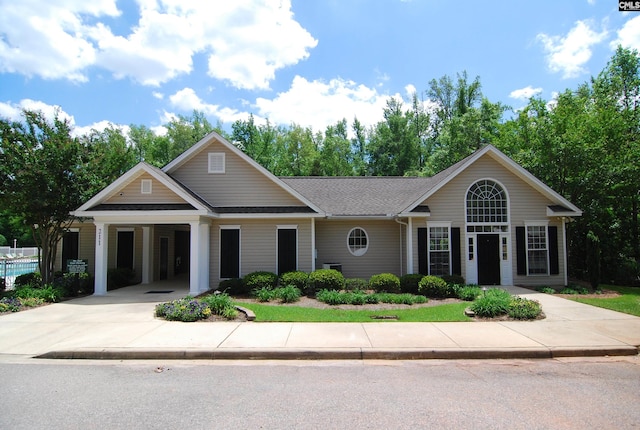 view of front of home with an attached carport, driveway, and roof with shingles