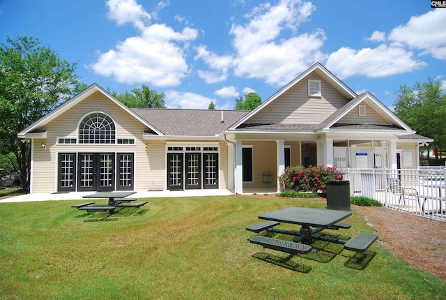 rear view of house with fence, a lawn, and a shingled roof