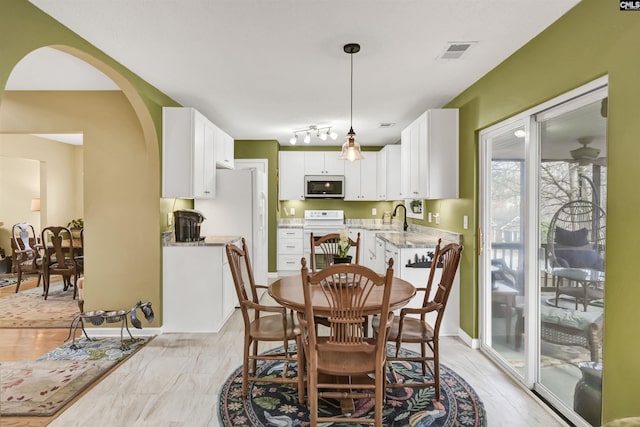 dining area featuring rail lighting, arched walkways, and visible vents