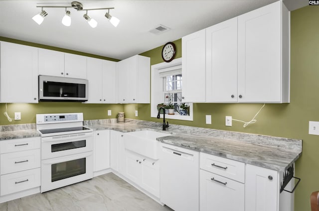 kitchen with a sink, visible vents, white appliances, and white cabinetry