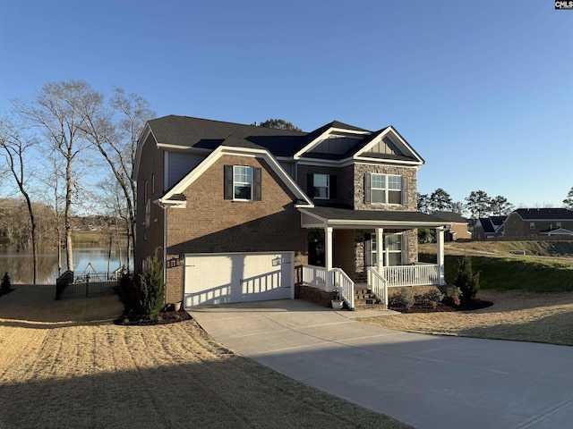 craftsman inspired home featuring brick siding, a water view, concrete driveway, covered porch, and a garage