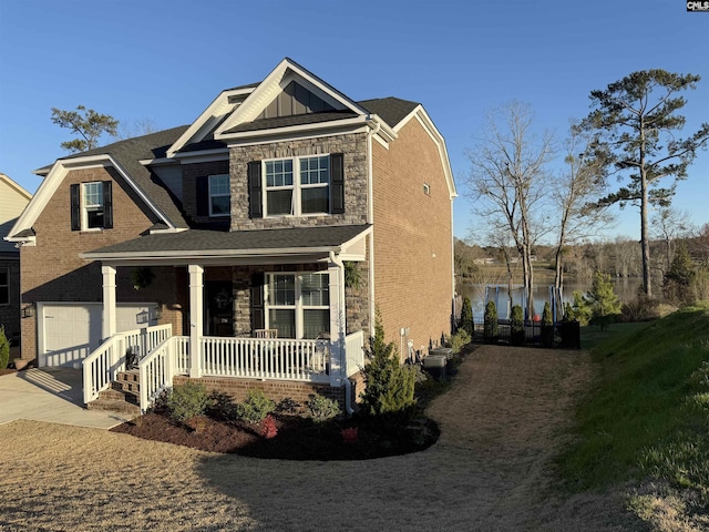 view of front of property featuring board and batten siding, a water view, concrete driveway, covered porch, and a garage