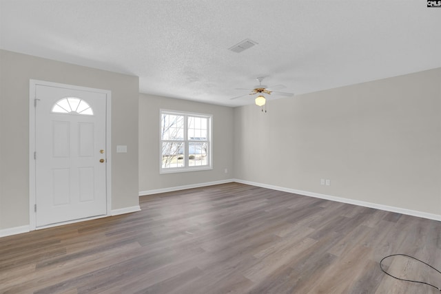 foyer with visible vents, a ceiling fan, a textured ceiling, wood finished floors, and baseboards