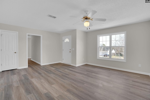 interior space with visible vents, baseboards, a textured ceiling, and wood finished floors