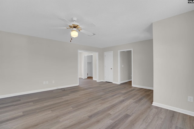 unfurnished room featuring ceiling fan, a textured ceiling, baseboards, and wood finished floors