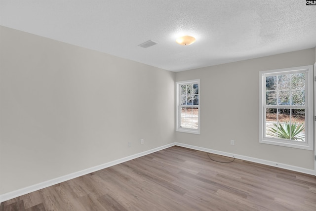 unfurnished room featuring plenty of natural light, wood finished floors, and baseboards