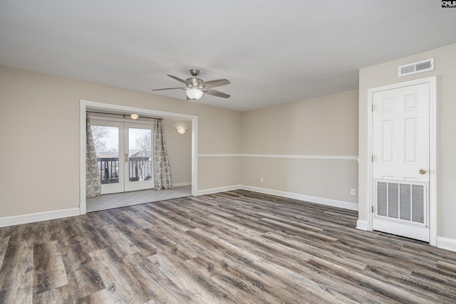 unfurnished room with a ceiling fan, wood finished floors, visible vents, and baseboards