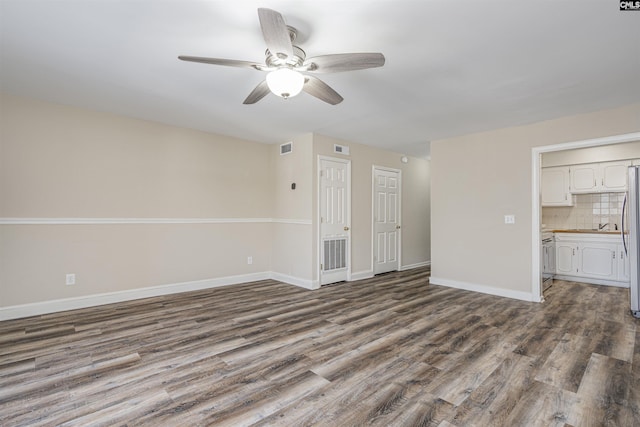 unfurnished living room with visible vents, baseboards, dark wood-type flooring, and ceiling fan