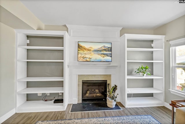 living room featuring a fireplace with flush hearth, wood finished floors, and baseboards