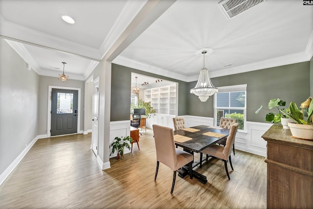 dining area featuring a chandelier, a wainscoted wall, visible vents, and wood finished floors