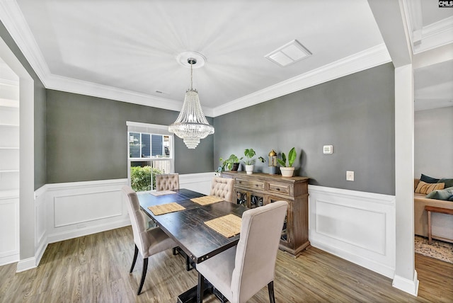 dining room featuring a chandelier, wainscoting, ornamental molding, and wood finished floors