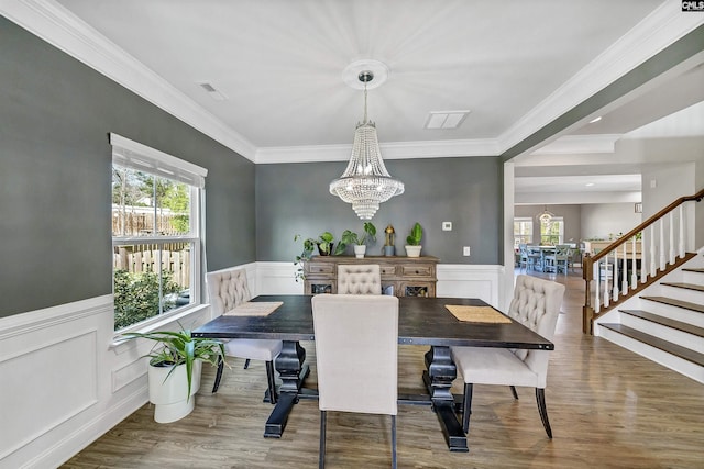 dining room featuring visible vents, a chandelier, a wainscoted wall, stairs, and wood finished floors