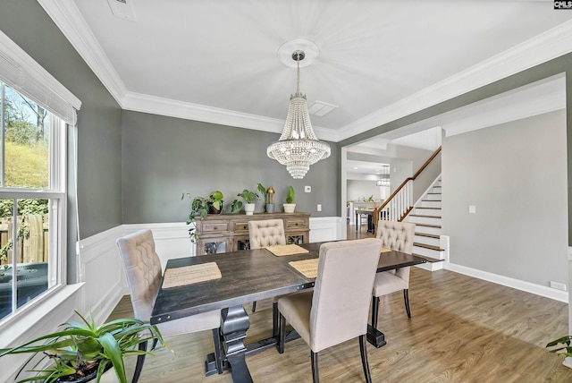 dining space featuring stairway, wainscoting, crown molding, and wood finished floors