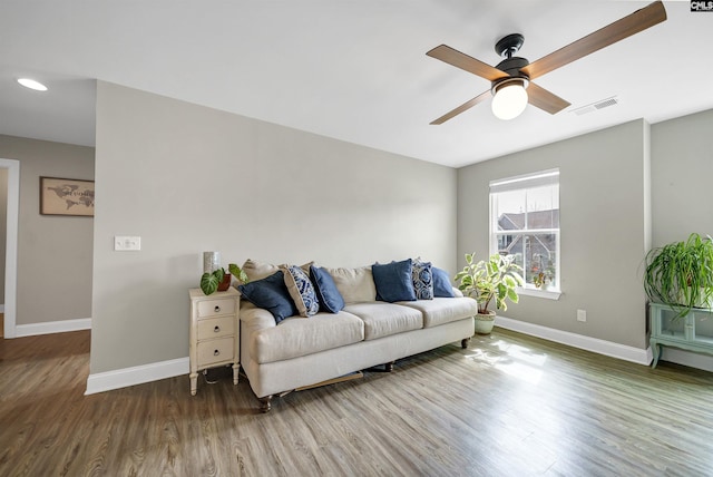 living area with ceiling fan, visible vents, baseboards, and wood finished floors