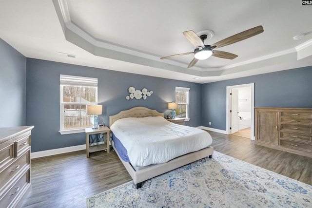 bedroom with crown molding, ceiling fan, baseboards, a tray ceiling, and wood finished floors