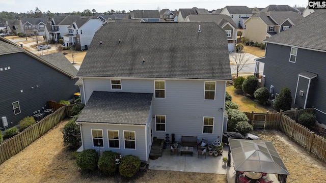 back of house featuring a residential view, roof with shingles, a fenced backyard, and a patio area