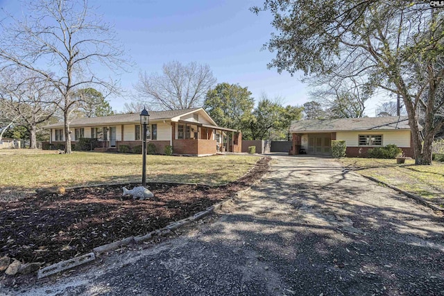 ranch-style house featuring brick siding, gravel driveway, and a front lawn