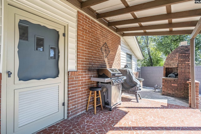 view of patio with an outdoor brick fireplace, area for grilling, and fence