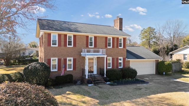 view of front of property with brick siding, a chimney, a balcony, a garage, and driveway