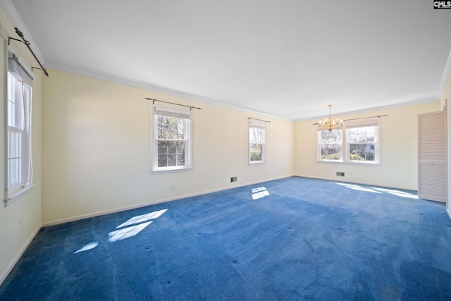 carpeted spare room featuring a wealth of natural light, baseboards, a notable chandelier, and ornamental molding