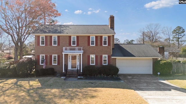 view of front facade with brick siding, an attached garage, a front lawn, a chimney, and driveway