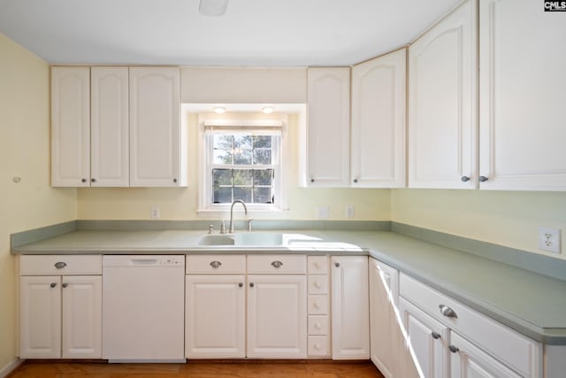 kitchen featuring dishwasher, white cabinetry, light countertops, and a sink