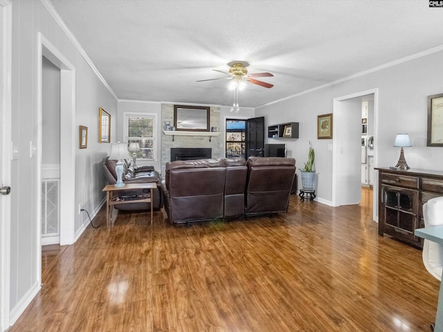 living room with visible vents, a fireplace, a ceiling fan, and wood finished floors