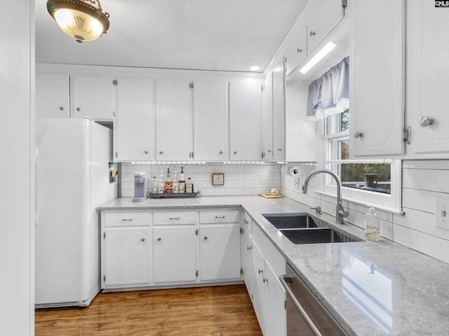 kitchen featuring a sink, white cabinetry, light wood-style flooring, and freestanding refrigerator