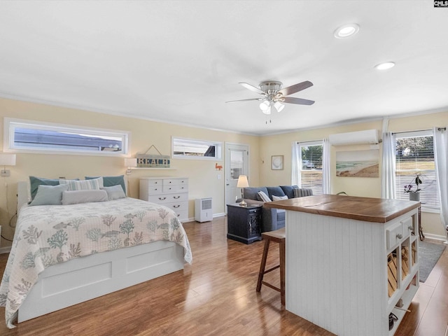 bedroom with a ceiling fan, wood finished floors, baseboards, recessed lighting, and a wall mounted air conditioner