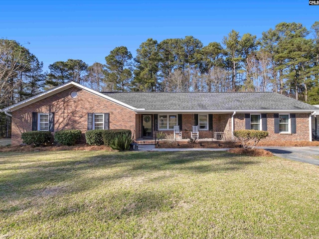 ranch-style house featuring a front yard, brick siding, covered porch, and a shingled roof