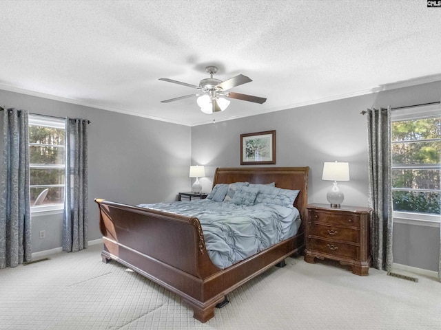 carpeted bedroom with crown molding, a ceiling fan, visible vents, and baseboards