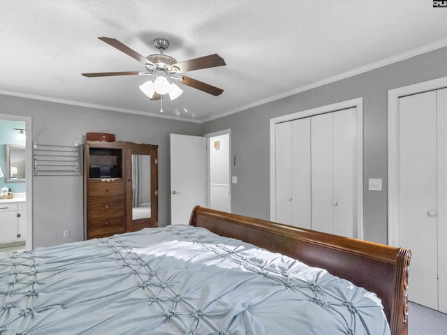 bedroom featuring ceiling fan, connected bathroom, two closets, and ornamental molding