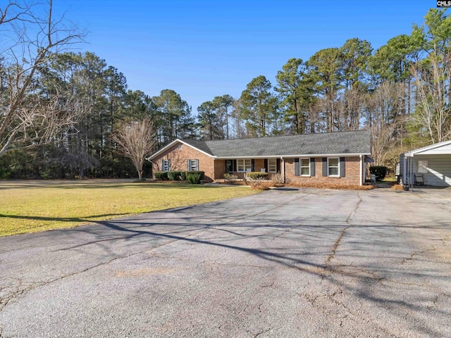 ranch-style house with a front yard, a porch, brick siding, and aphalt driveway