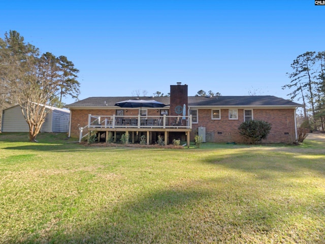 rear view of property featuring crawl space, brick siding, a wooden deck, and a chimney