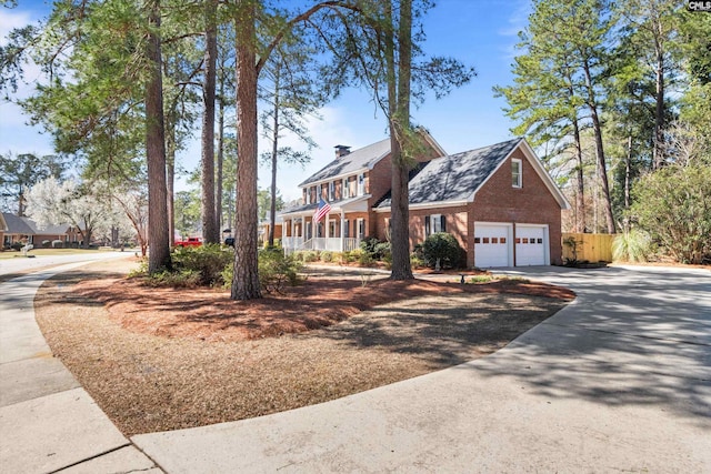 view of front of property featuring brick siding, driveway, a chimney, and fence