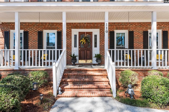 entrance to property featuring brick siding and covered porch