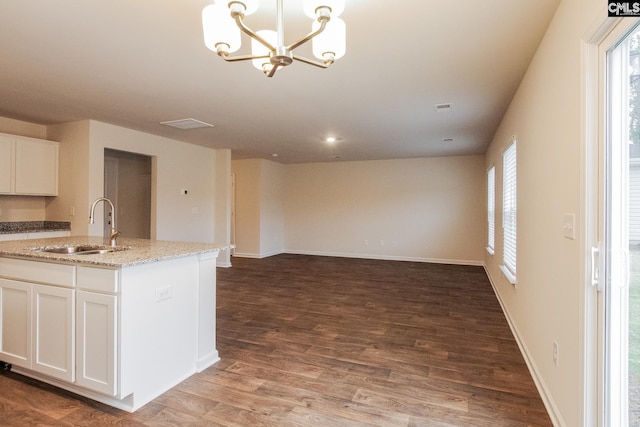 kitchen featuring white cabinetry, wood finished floors, baseboards, and a sink