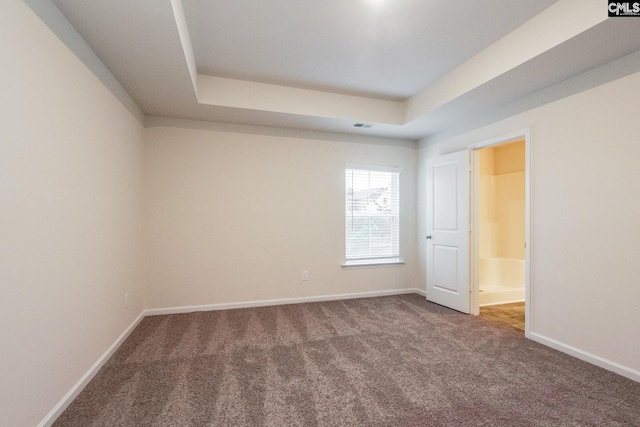 unfurnished room featuring a tray ceiling, visible vents, baseboards, and carpet floors